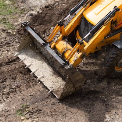 Earthwork bulldozer on the line. The work of a universal machine designed for digging soil, planning sites for construction, cleaning the territory, digging trenches.